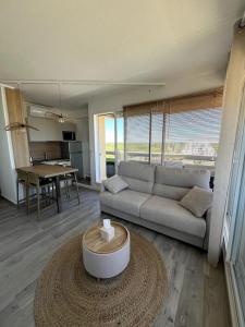 a living room with a couch and a table at Sublime Appart Vue mer Piscine Clim in La Grande-Motte