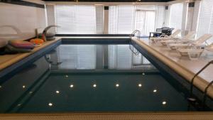 a swimming pool with a table and chairs in it at Buzovna Villa in Baku