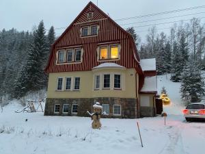 a teddy bear standing in the snow in front of a house at vilavítkovice in Vítkovice