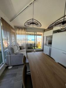 a living room with a table and a couch at Sublime Appart Vue mer Piscine Clim in La Grande-Motte
