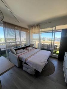 a bedroom with a bed in a room with windows at Sublime Appart Vue mer Piscine Clim in La Grande-Motte