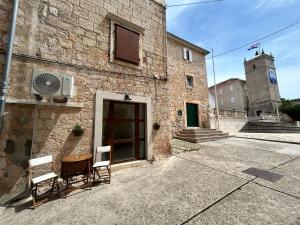 a building with two chairs and a table and a window at Apartment San Pietro in Supetar