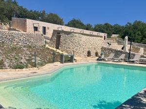a large swimming pool in front of a stone building at DONNAPAOLA MODERN FARM in Altamura