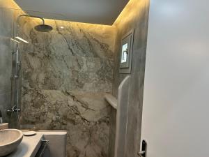 a bathroom with a stone shower and a sink at George Studios 2 in Kithnos