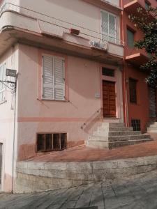 a pink building with stairs and a door at Sa Sartoria in Bolotana