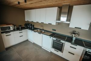 a kitchen with white cabinets and a sink at Le Noir Flohay 30 pers - Malmedy, vue, wellness in Malmedy