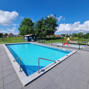 a swimming pool in a park with a person jumping into it at Luxus Familienvilla mit Jacuzzi & Sauna in Tzummarum