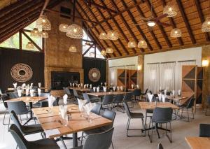 a restaurant with wooden tables and chairs and chandeliers at Olifants River Lodge by Dream Resorts in Middelburg
