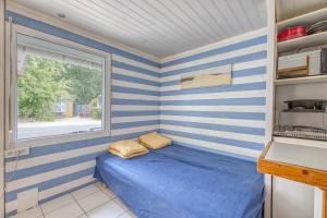 a small bedroom with a blue and white striped wall at Chalet B Village Vacances in Gujan-Mestras