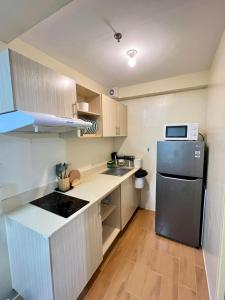 a small kitchen with a refrigerator and a microwave at Seawind Condo 2 BR Near Airport and Facing Samal in Davao City