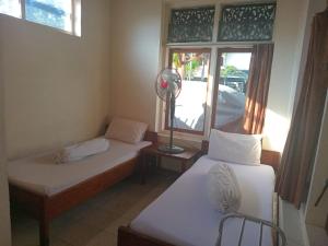 two beds in a room with a fan and a window at Hotel Wisata in Labuan Bajo