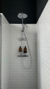 a shower in a white tiled bathroom with two bottles at Hospice St Nicolas in Troyes