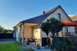 ein Haus mit einem orangefarbenen Sonnenschirm und einer Terrasse in der Unterkunft Cottbus Merzdorf Bauernhaus Ferienhaus in Cottbus