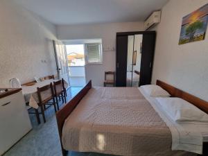 a bedroom with a bed and a kitchen and a table at Apartmani Bada in Pakoštane