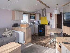 a kitchen and living room with a couch and a table at Pinewoods Beach no.5 - sleeps 6 – no dogs in Wells next the Sea