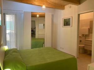 a bedroom with a green bed and a mirror at Casa Gaia, La Casa Sui Tetti in Isolabona