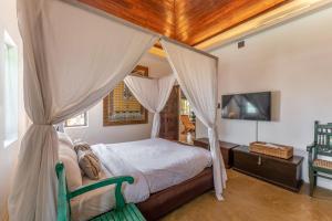 a bedroom with a canopy bed and a television at Villa Naina, Marari beach in Alleppey