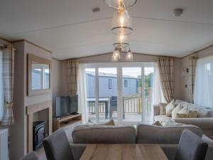 a living room with a couch and a table and a tv at Pinewoods Beach Luxe no.4 – dog friendly in Wells next the Sea