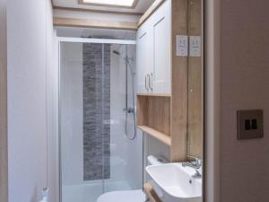 a bathroom with a shower and a toilet and a sink at Pinewoods Beach Luxe no.4 – dog friendly in Wells next the Sea +2 photos