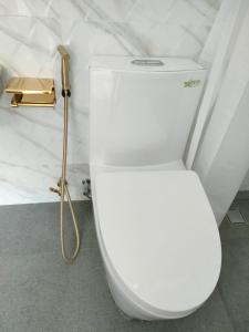 a white toilet in a bathroom with a gold hose at Villa Emas Mulia Uluwatu Standard 5 in Uluwatu
