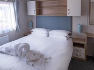 a bedroom with a white bed with a towel on it at Pinewoods Beach no.3 - sleeps 6 – dog friendly in Wells next the Sea