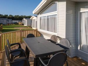 a wooden deck with a table and chairs on a house at Pinewoods Beach no.3 - sleeps 6 – dog friendly in Wells next the Sea