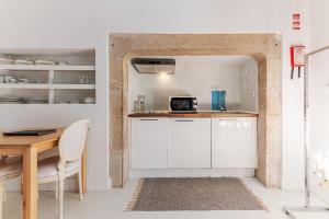 Una cocina con gabinetes blancos y una mesa. en Portas do Castelo Apartments, en Lisboa