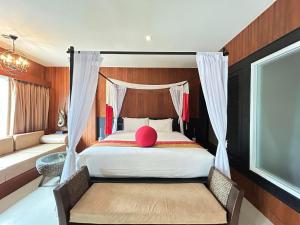 a bedroom with a bed with a pink pillow on it at Benyada Lodge - Surin Beach in Surin Beach