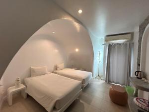 two beds in a room with an arched ceiling at Benyada Lodge - Surin Beach in Surin Beach