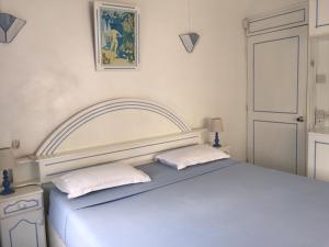een witte slaapkamer met een bed met 2 kussens bij Studio Manguillier in Trou dʼ Eau Douce