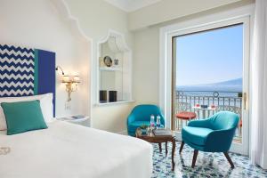 a bedroom with a bed and two chairs and a large window at Grand Hotel Ambasciatori in Sorrento +37 photos