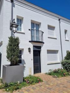 a white brick building with a balcony and a tree at Garden Alley House 8 personnes in Serris +37 photos