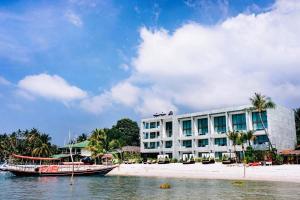 塔林甘海滩The Beach Samui的海滩边的一家酒店和一艘在水中的船