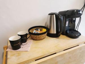 a coffee maker and two coffee cups on a wooden cabinet at L'essentiel in Évreux