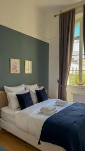 a large bed with blue and white pillows and a window at Hospice St Nicolas in Troyes