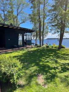 a house in the grass next to a body of water at Moderni rantasauna ja -mökki in Joensuu