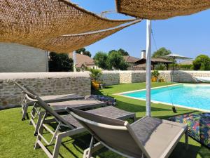a patio with chairs and an umbrella and a pool at LES BOHEMIELLES Chambre Mathilda in Cartelègue