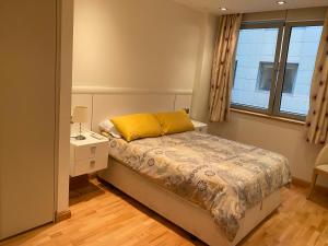 a bedroom with a bed with a yellow pillow and a window at Swimming pools Apartment in Ocean Village - 2 bed 2 bath Rock view in Gibraltar +22 photos