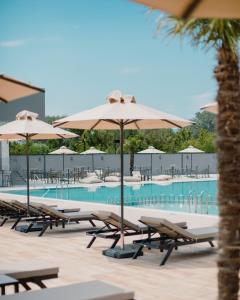 a pool with tables and umbrellas and chairs at Casino Motel Senator in Gevgelija