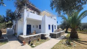 a white villa with palm trees in front of it at Klimis apartments in Sifnos