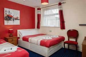 a bedroom with two beds with red walls and a window at Lanayr Hotel in Blackpool
