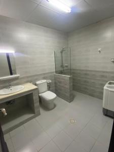 a bathroom with a toilet and a shower and a sink at Jawhrat Furnished Apartment in Salalah