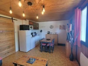 a kitchen with a table and a white refrigerator at Appartement au RDC d'un Chalet - Proche Ski/Randonnées - Terrasse Sud - 4 pers - FR-1-393-150 in Saint-Michel-de-Chaillol