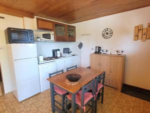 a kitchen with a table and a white refrigerator at Appartement au RDC d'un Chalet - Proche Ski/Randonnées - Terrasse Sud - 4 pers - FR-1-393-150 in Saint-Michel-de-Chaillol +5 photos