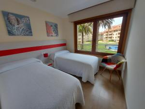 a hotel room with two beds and a window at Magnífico apartamento en el corazón de La Toja in Isla de la Toja +9 photos