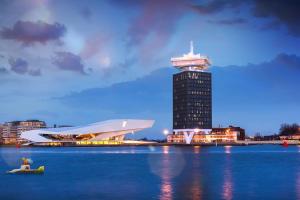 阿姆斯特丹Bed and breakfast private accommodation at Amsterdam Houseboat的水体旁有钟楼的房子