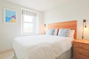 a bedroom with a large white bed and a window at North View cottage. Shaldon village. in Shaldon