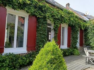 a house covered in ivy with a bench on a deck at La Aussière, Maison avec jardin à 500m de la plage pour 4 à 6 pers in Cayeux-sur-Mer