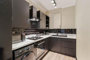 a kitchen with white cabinets and a stove top oven at Apartment in Altrincham Centre in Altrincham
