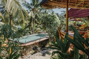 an outdoor swimming pool in a resort with palm trees at The Tamban Jukung in Nusa Penida